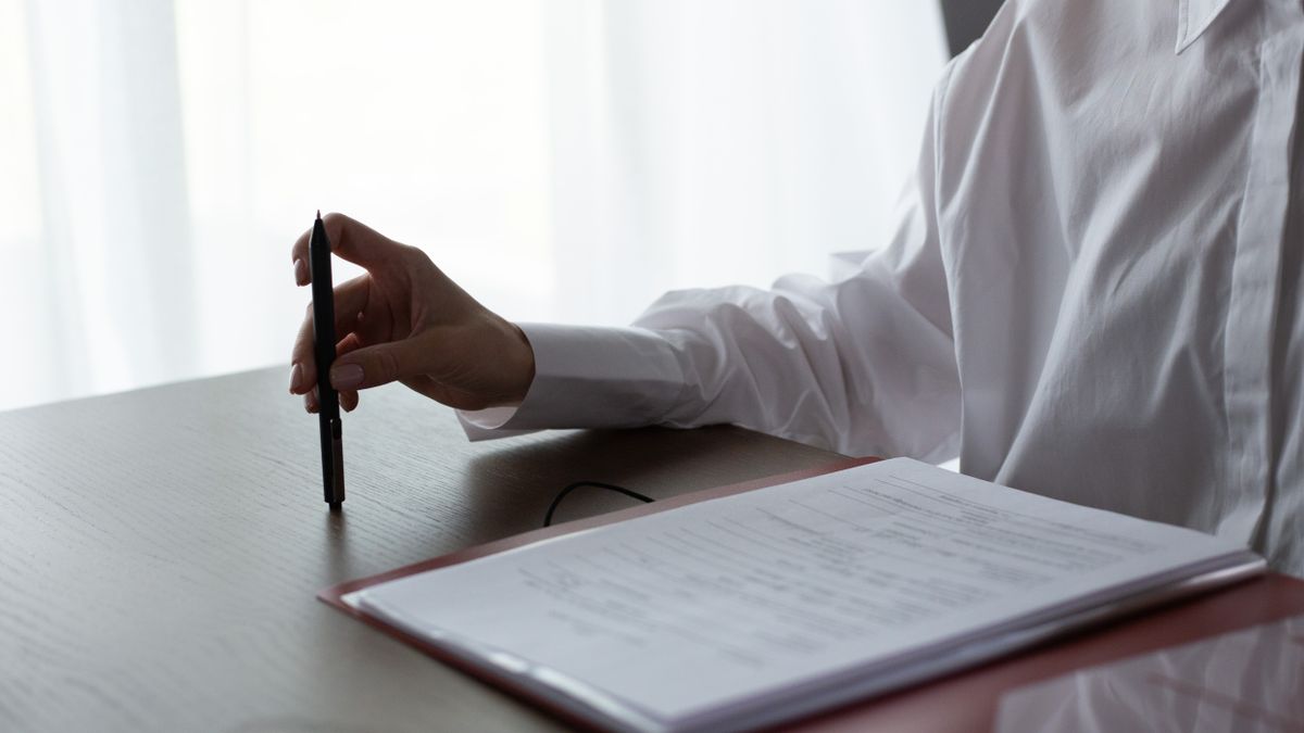 A professional reviewing regulatory documents and folders at a desk